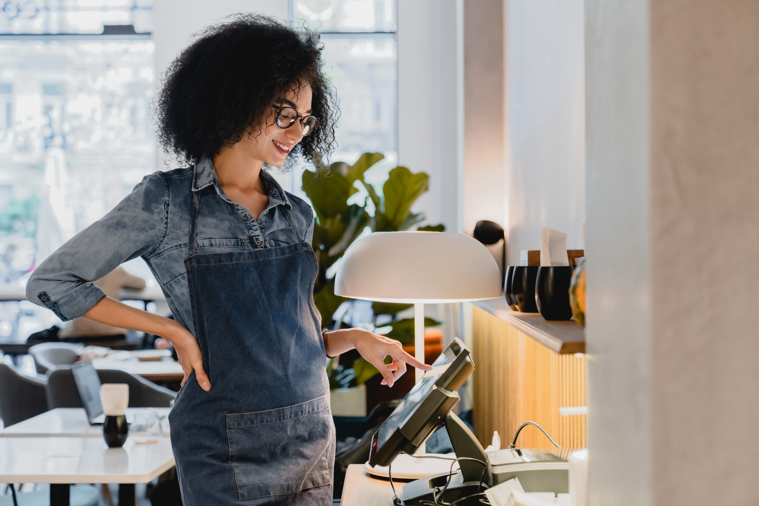 Waitress working at the cash point in spacious cafe