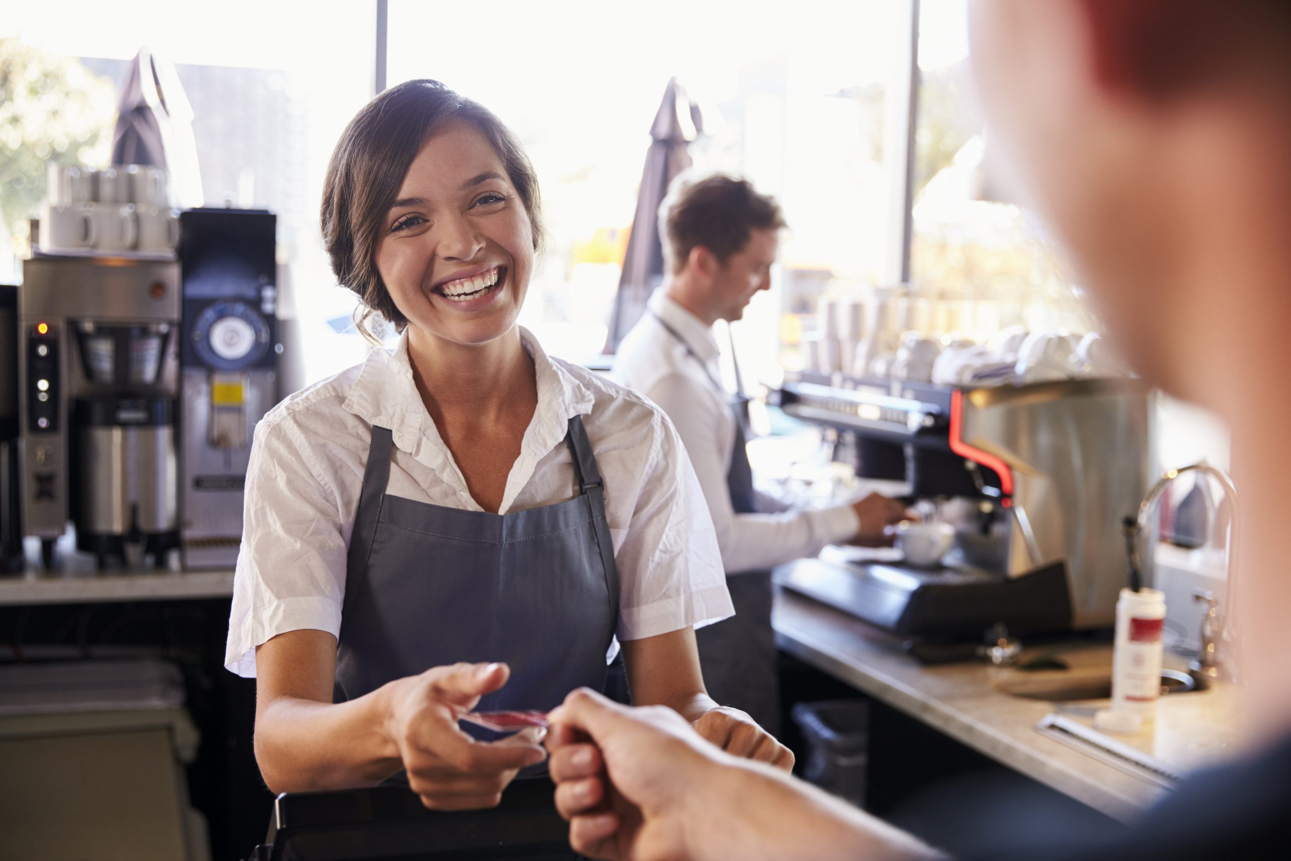 Cashier Accepts Card Payment From Customer In Delicatessen